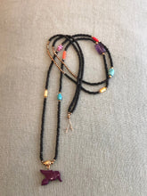 Charger l'image dans la galerie, Sautoir en perles de rocaille noires, perles hématites dorées et petites perles semi précieuses colorées. Pendentif petit animal oiseau violet.