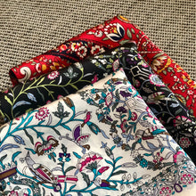 Charger l'image dans la galerie, 3 petits carrés de soie petites fleurs sur fond noir, blanc, ou rouge pliés et posés sur un coussin chiné gris