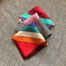 Charger l'image dans la galerie, 3 petits carrées de soie vintage et colorés , pliés sur un coussin chiné gris