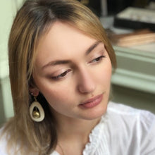Charger l'image dans la galerie, Gros plan jeune fille avec une boucle d'oreille en bois blanc ajouré et perle ronde en laiton doré. Ambiance douce et romantique.