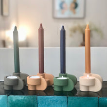 Charger l'image dans la galerie, 4 bougeoirs reversibles chocolat, terra, green olive et nude en terre cuite mate avec bougies sur un bar en zélig vert foncé.