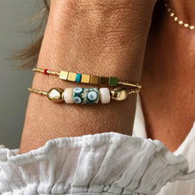 Charger l'image dans la galerie, Bracelet Cocody , perle africaine en pâte de verre et perle galet plaqué or sur miyuki or sur poignet et chemise blanche