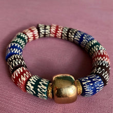 Charger l'image dans la galerie, bracelet en perles céramiques multicolores du Ghana et grosse perle large dorée sur un tissu rose