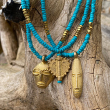 Charger l'image dans la galerie, Ensemble de 3 colliers en perles heishi en howlite turquoise, hématite or et pendentifs africains en laiton doré posés sur une branche d'arbre vieilli par le temps