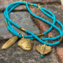 Charger l'image dans la galerie, Ensemble de 3 colliers en perles heishi en howlite turquoise, hématite or et pendentifs africains en laiton doré posés sur de la veille pierre