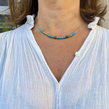 Charger l'image dans la galerie, Collier surfeur turquoise et or sur un cou de jolie brune en chemise blanche