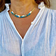 Charger l'image dans la galerie, Collier surfeur turquoise et or et collier surfeur blanc et or sur un cou de jolie brune en chemise blanche