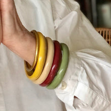 Charger l'image dans la galerie, Bracelets jonc divers bordeaux, kaki clair, crème et jaune en résine style vintage sur poignet de femme en chemise blanche