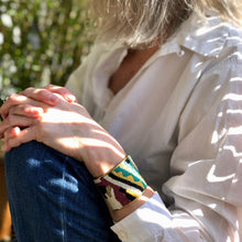 Charger l'image dans la galerie, Bracelet manchette perlée motif couleurs et laiton doré portée par une femme blonde chemise blanche et jean