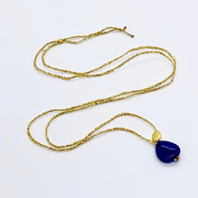 Charger l'image dans la galerie, Sautoir talisman bohème composé d'une perle de verre chunky bleu nuit et d'une perle galet plaqué or sur fil d'or