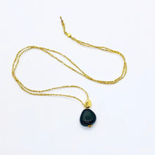 Charger l'image dans la galerie, Sautoir talisman bohème composé d'une perle de verre chunky noire et d'une perle galet plaqué or sur fil d'or