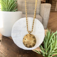 Charger l'image dans la galerie, Gros plan sur pendentif rond multispirales en laiton doré sur une chaine torsadée or. Posé sur un rondin de bois peint en blanc.