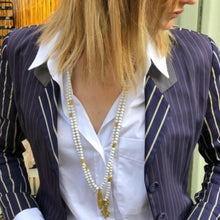 Charger l'image dans la galerie, Mise en situation de 2 sautoirs perles de bois blanc et pendentif laiton doré sur femme blonde avec chemise blanche et veste bleue marine à fines rayures. Style mix and match casual-ethnique