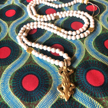 Charger l'image dans la galerie, Long sautoir en perles de bois blanc et laiton dorées avec pendentif salamandre en laiton doré. Présentation sur tissu africain couleurs vives