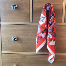 Charger l'image dans la galerie, petit carré de soie dessins naifs sur fond rouge accroché à un bouton d'un tiroir d'une commode en bois naturel