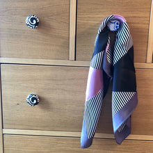 Charger l'image dans la galerie, petit carré de soie avec bandes parme marine et rayées accroché à un bouton d'un tiroir d'une commode en bois naturel