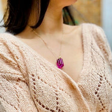 Charger l'image dans la galerie, sautoir talisman bohème cannelé rose framboise sur décolleté femme brune vêtue d'un pull fin rose pâle