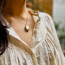 Charger l'image dans la galerie, gros plan sur sautoir talisman bohème nacre calisson porté court sur décolleté femme brune vétue d'une blouse crème à fins liserets dorés.