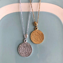 Charger l'image dans la galerie, 2 sautoirs talimans bohèmes médaille gravée or et argent montés sur fil or et argent et petite perle galet or et argent sur fond bleu vintage et blanc.