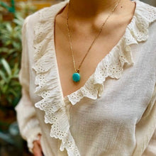 Charger l'image dans la galerie, Plan serré sur buste de femme portant un sautoir talisman bohème en amazonite hexagonale et vêtue d'une blouse col V à volants en piqué de coton blanc.