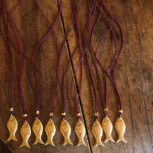 Plusieurs sautoirs avec pendentif poisson en laiton doré montés sur un lien de cuir de couleur bordeaux tirant sur le rose foncé