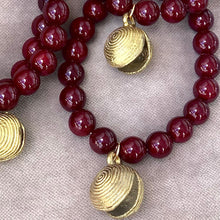 Charger l&#39;image dans la galerie, Bracelet perles rondes lisses bordeaux et breloque africaine en laiton doré

