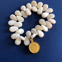 Charger l&#39;image dans la galerie, Bracelet élastique en perles goutte de nacre blanche avec une pampille doré sur fond bleu

