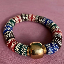 Charger l&#39;image dans la galerie,  bracelet en perles céramiques multicolores du Ghana et grosse perle large dorée sur un tissu rose

