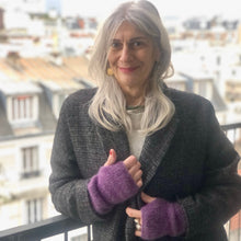 Charger l&#39;image dans la galerie, mitaines tricotées main en alpaga et de couleurs violette portées par une femme au longs cheveux blancs en grand manteau gris chiné
