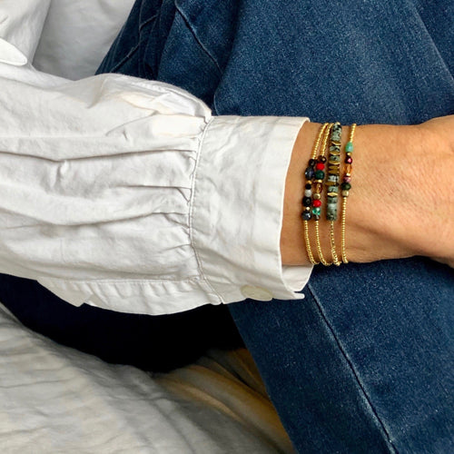 série de bracelets miyukis précieux or et bracelet surfeur , sur mannequin chemise blanche et jean