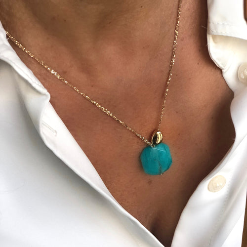 collier sautoir perle semi précieuse turquoise montée sur un fil d'or et une perle galet or sur un décolletée chemise blanche