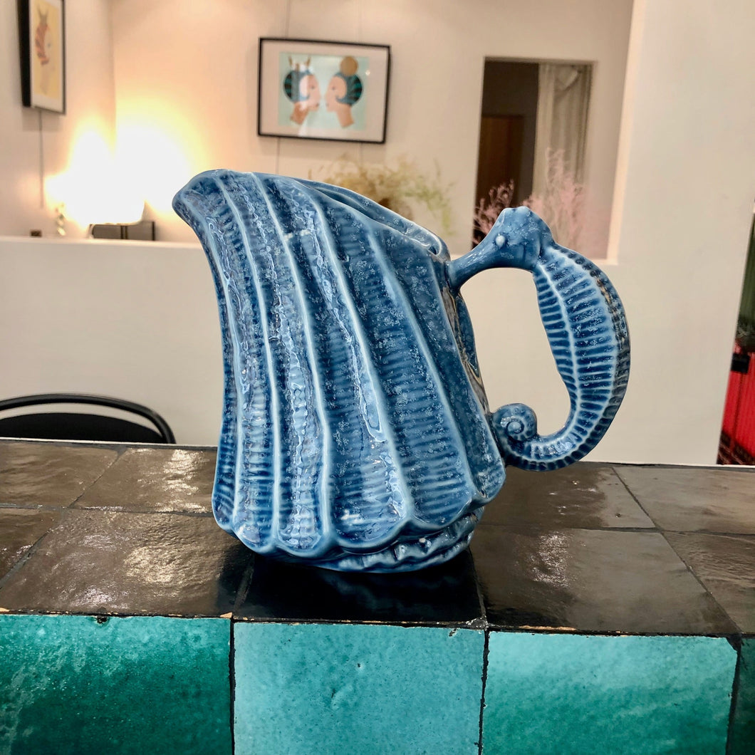 pichet céramique bleu avec poignée en forme d'hippocampe sur un bar en zélig noir et vert