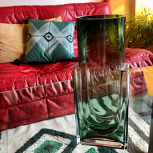 Charger l&#39;image dans la galerie, Gros plan vase en verre vert sur table en verre transparente et canapé Togo cuir rouge en arrière plan 

